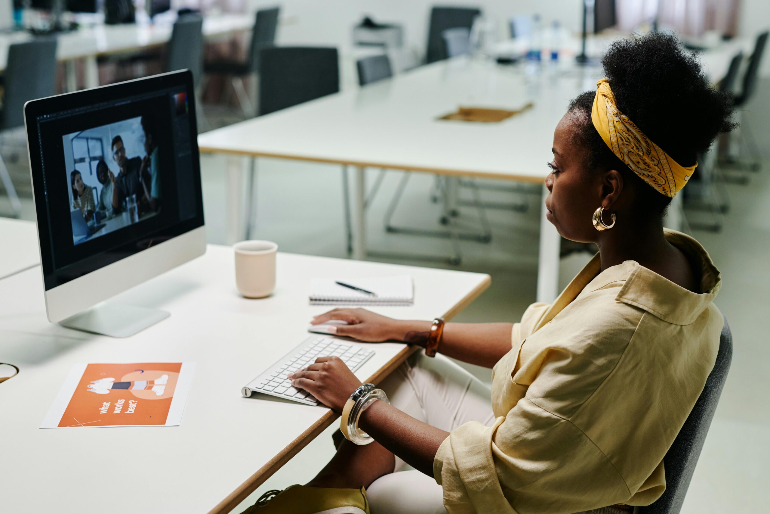 Young black woman using computer for video editing in a modern office setting.